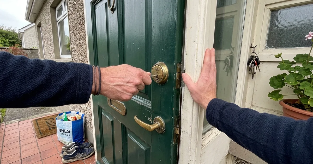 Hand struggling to turn a key in a front door lock